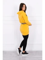 Šaty zdobené stuhou a nápismi v horčicovej farbe