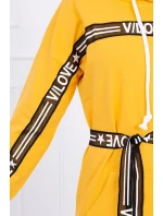 Šaty zdobené stuhou a nápismi v horčicovej farbe